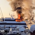 Fire engulfs opulent yacht in St Tropez, spewing thick smoke.
